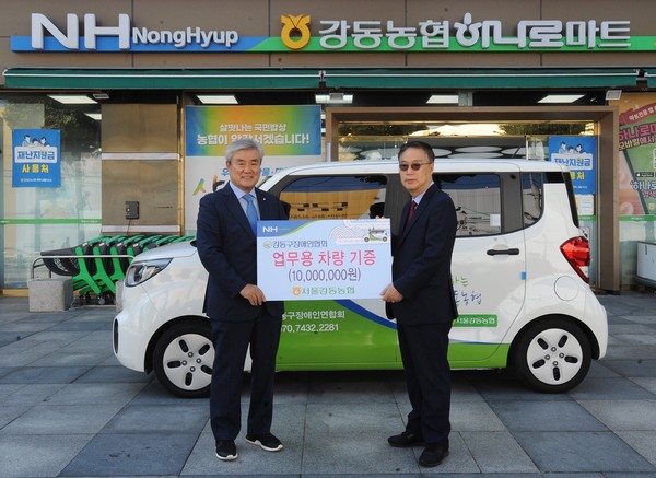 박성직 조합장(왼쪽)이 박건용 강동장애인협회 대표에게 업무용 차량을 전달하고 있다.