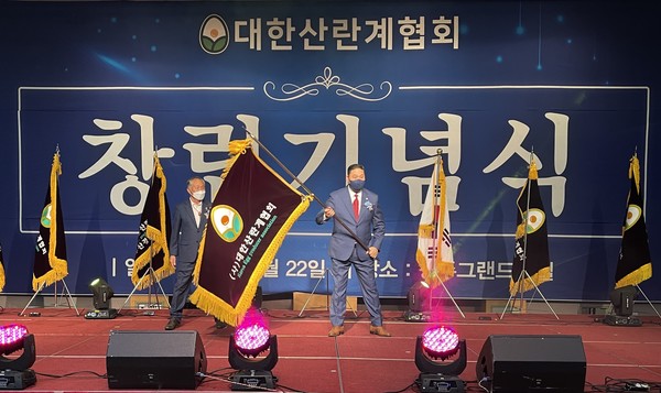 안두영 대한산란계협회장이 지난 22일 열린 산란계협회 창립기념식에서 협회기를 전달 받은 후 흔들고 있다. 