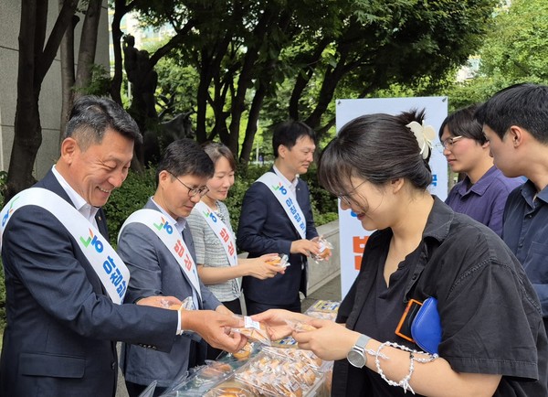 김상수 농협서울본부장(왼쪽)이 쌀 소비 촉진을 위해 영업점 방문 고객에게 쌀로 만든 빵을 나눠주고 있다.
