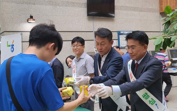 홍성표 송파농협 조합장(오른쪽 1번째)과 김상수 농협서울본부장(가운데)이 송파도서관 이용객에게 밥버거와 식혜를 나눠주고 있다.