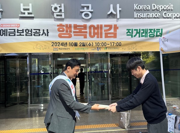 김인수 농협 서울경제지원단 단장(왼쪽)이 예금보험공사에서 열린 직거래장터에서 우리 쌀 소비촉진을 위해 햅쌀을 방문고객에게 전달하고 있다.