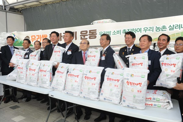 우리 쌀 팔아주기 운동 발대식에서 박준식 조합장(왼쪽에서 일곱 번째)을 비롯한 내빈들이 쌀을 들어 보이고 있다.