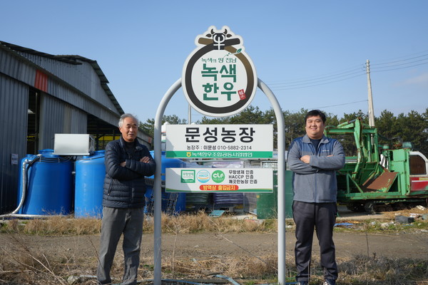 이평관 대표와 그의 아들 이문성 씨가 문성농장 현판 옆에서 포즈를 취하고 있다.