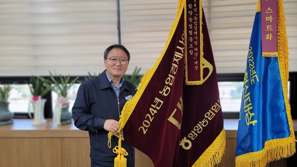 농업경제사업대상 대상수상기와 함께 포즈를 취하고 있는 강 조합장.