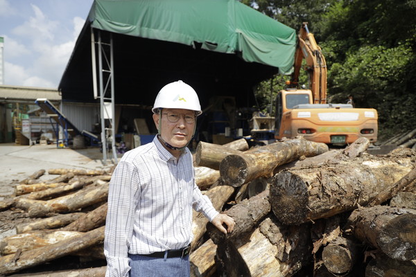 펠릿 원목을 앞에 두고 최 조합장이 설명하고 있다.