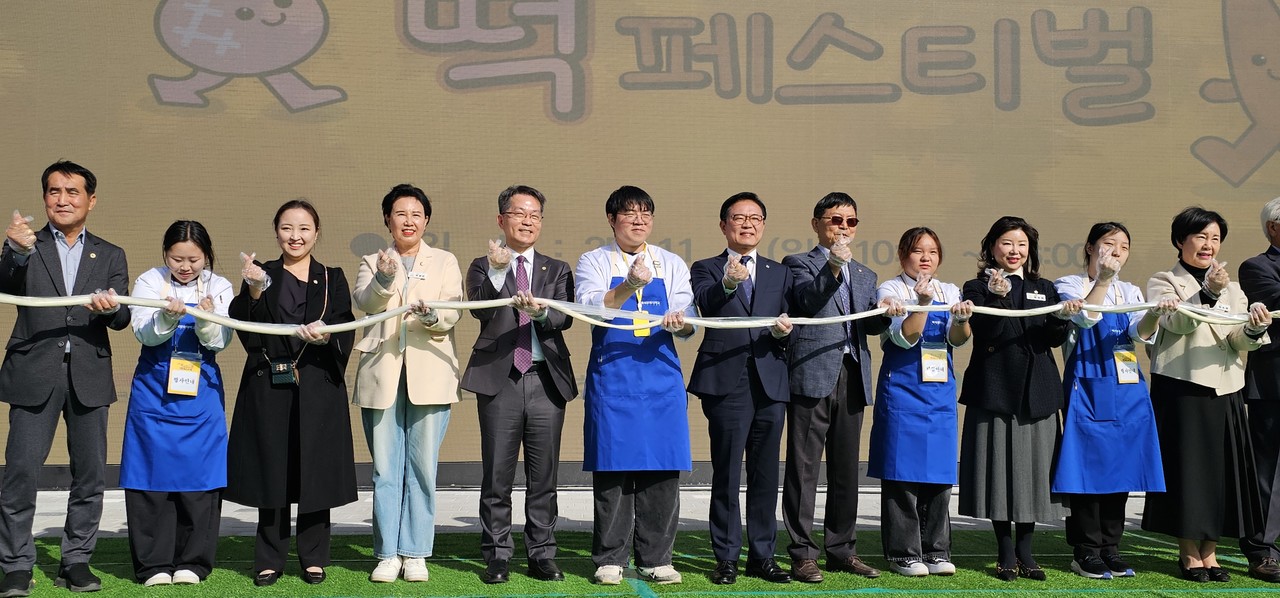 가래떡 뽑기 퍼포먼스에 참여한 주요 참석자들이 긴 가래떡을 함께 들어 보이며 축제의 시작을 알리고 있다.