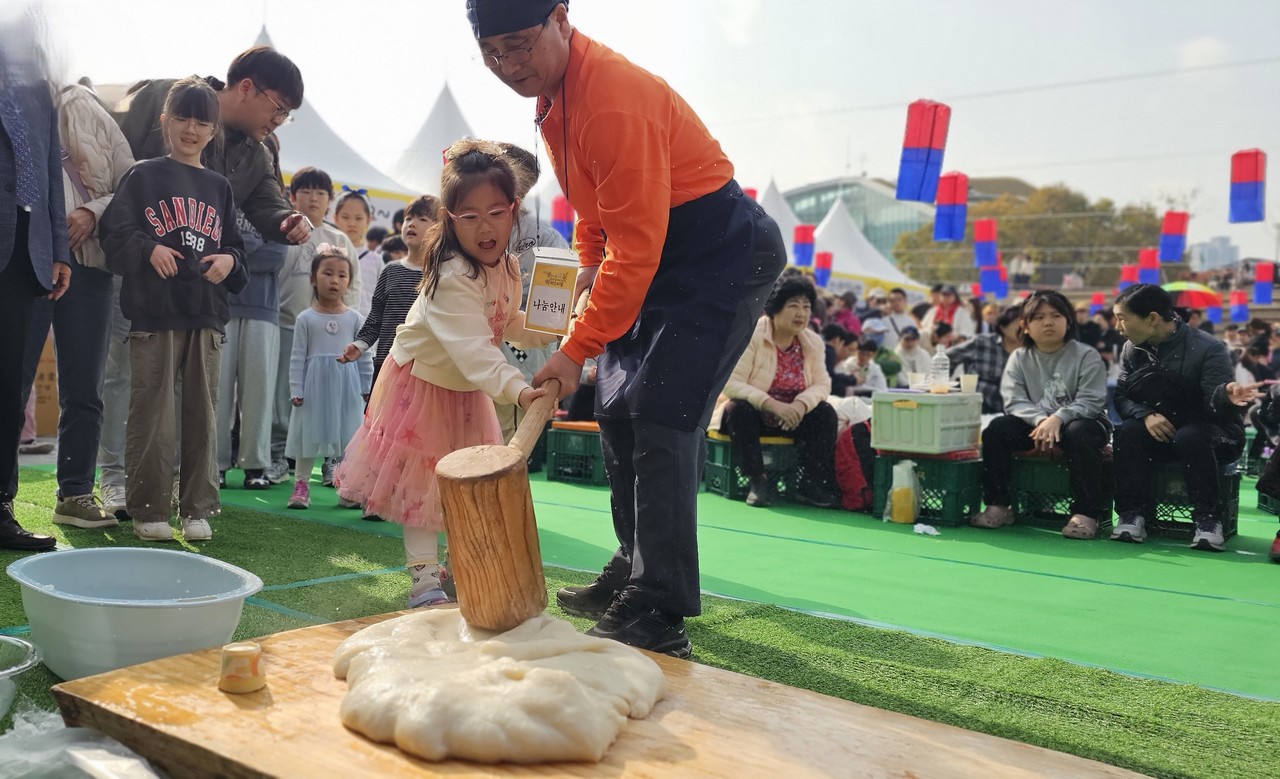 떡메치기 체험을 하고 있는 아이의 표정이 밝다