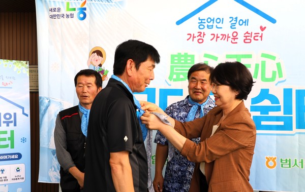 김숙희 범서농협 조합장(오른쪽)이 농업인에게 넥쿨러를 착용해 주며 폭염 속 농작업 안전과 온열질환 예방을 당부하고 있다.